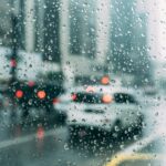 Blurred city traffic seen through a window with raindrops, a perfect rainy day scene.