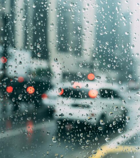Blurred city traffic seen through a window with raindrops, a perfect rainy day scene.