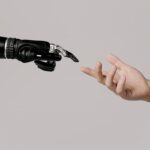 A human hand reaching to touch a bionic prosthetic hand on a white background.