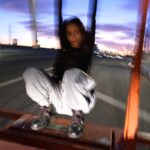 woman in black jacket and white pants sitting on brown wooden bench