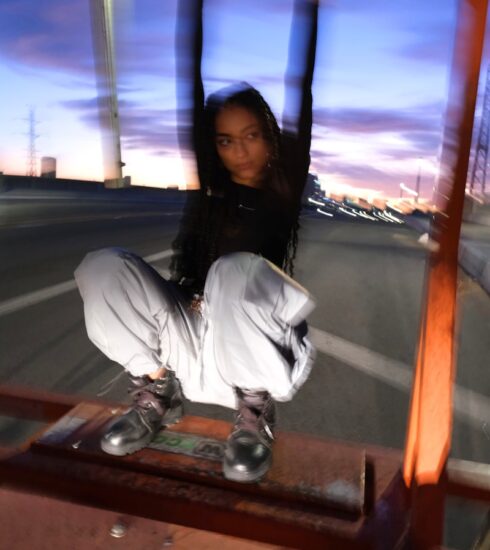 woman in black jacket and white pants sitting on brown wooden bench