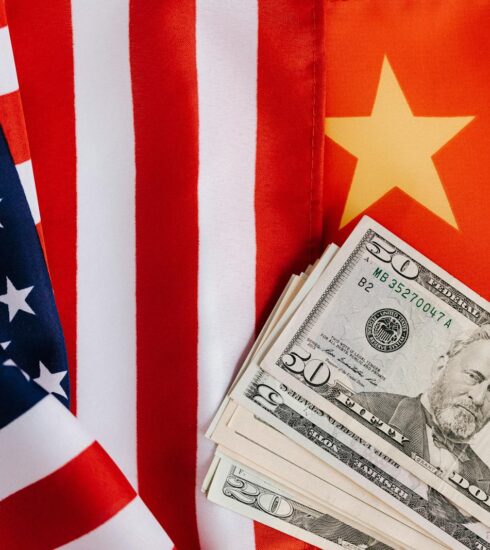 Close-up of US and China flags with US dollar bills, representing international trade and finance.